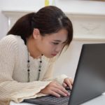 ノートパソコンで必死に作業する女性